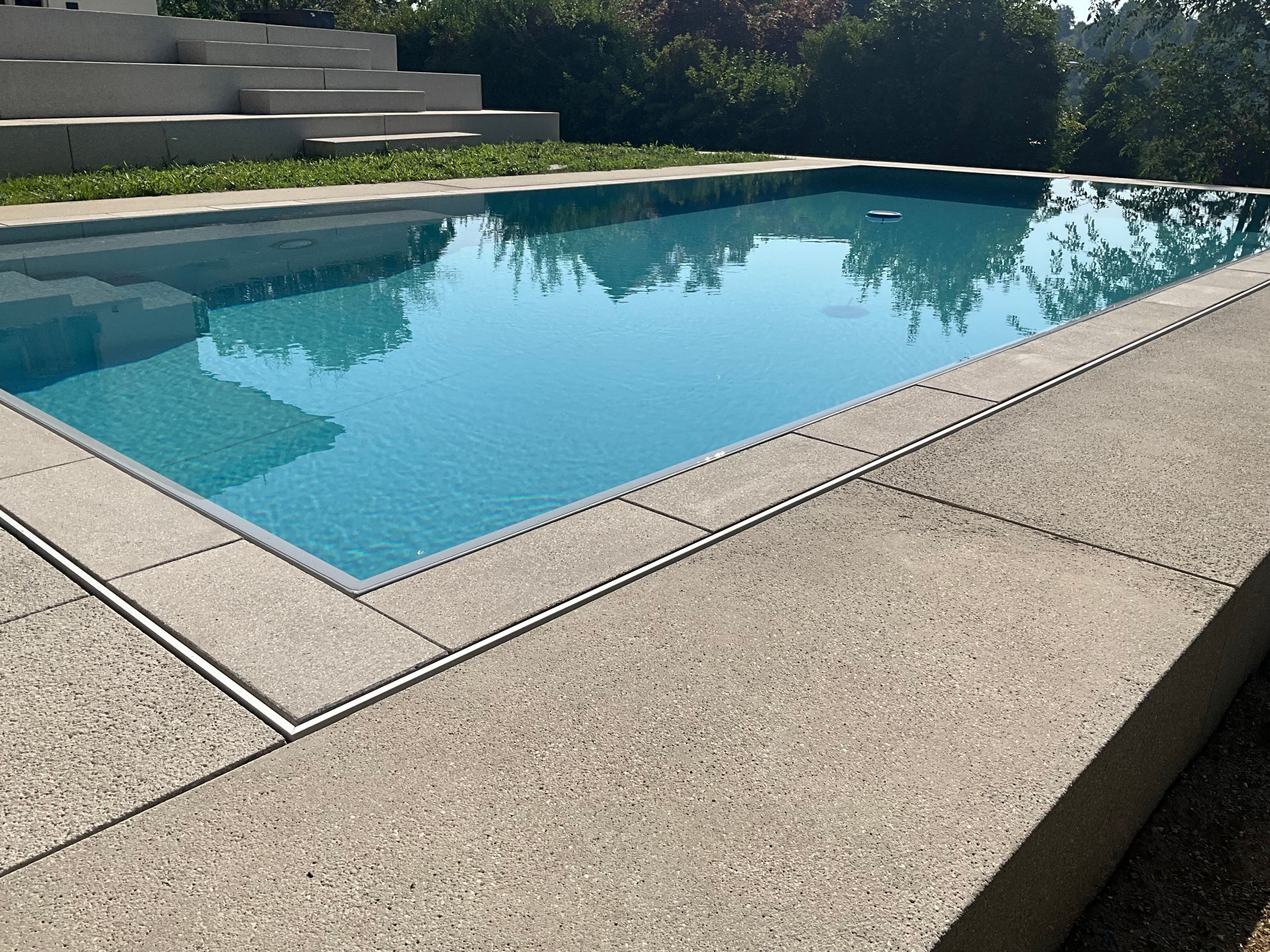 Überlaufpool mit Steineinlage, die Rinne verschwindet im Terrassenbelag